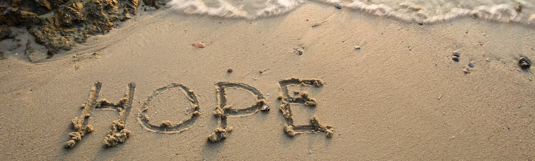 Hope written in sand at shoreline